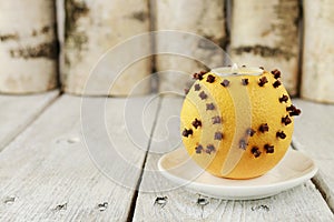 Orange pomander ball with candle on wooden table