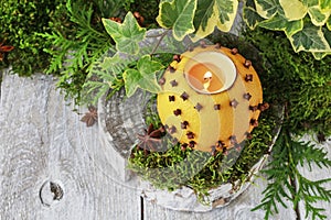 Orange pomander ball with candle on wooden table