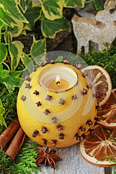 Orange pomander ball with candle on wooden table