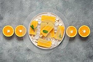 Orange popsicles, gray vintage background. Summer refreshing dessert. Top view, flat lay