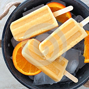 Orange popsicles in a rustic ice filled tin pail