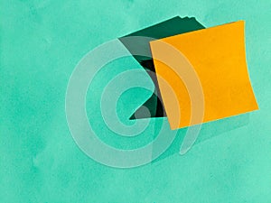 Orange Post-it Note Pad with Shadowing Against Soft Green Paper Background with Space for Text