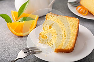 Orange pound cake slice on a plate, bundt cake topped with powdered sugar