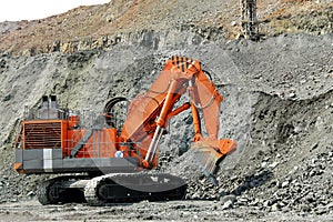 An orange power-shovel works in a career