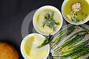 Orange pumpkin and asparagus soup in plates with cream on wooden background. Top view