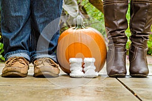 Orange pumpkin with baby shoes and parents shoes standing next t