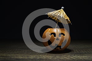 Orange Pumpkin Halloween with umbrella on wooden table in black background