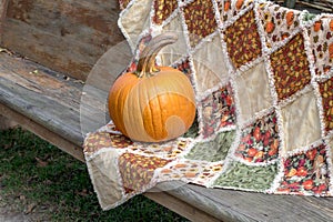 Orange pumpkin on a handmade fall quilt