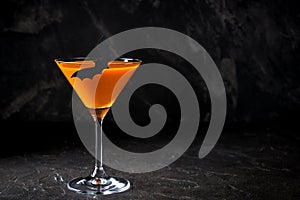 Orange pumpkin martini Halloween drink for party over black background. Copy space