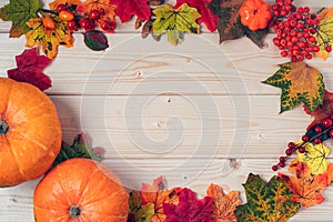 Orange pumpkins, maple leaf, berries and mock up paper blank on wooden background. Hello Fall greeting card, autumn time concept.