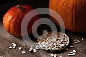 Orange pumpkins and pumpkin seeds on a wooden table, still life rustic style