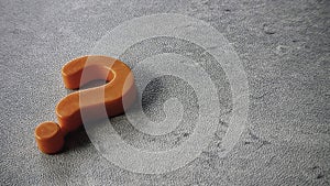 Orange question mark symbol on gray surface
