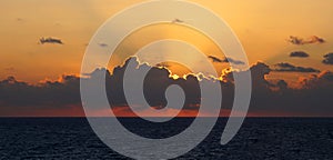 orange rays of the setting sun over the sea horizon