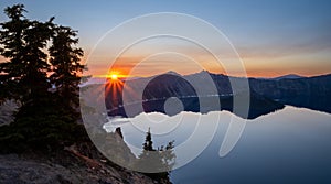 Orange Rays from Sunset Behind Mountains Over Crater Lake