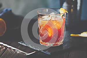 Orange or red coctail in an old fahion glass with citrus and ice cubes