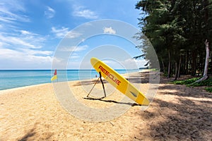 Orange rescue board and boundary flag on the beach at Mai Khao Beach, Phuket Province, Thailand