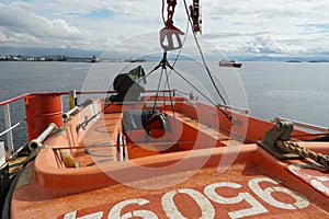 Orange rescue boat built from glass reinforced plastic material with outboard engine is secured by davit.