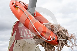 Orange rescue flotation ring seen located by the water`s edge of a flooded inland quarry.