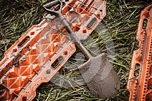 Orange rescue sand tracks and shovel on grass.