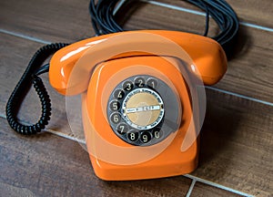 Orange retro telephone on wooden background