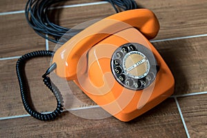 Orange retro telephone on wooden background