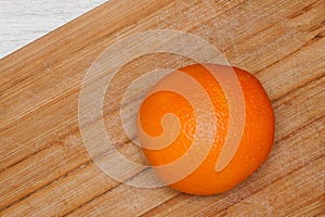 Orange ripe fruit on wooden board in kitchen.