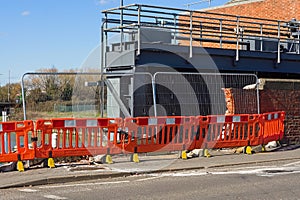 Orange road barriers in fornt of a damaged brick wall