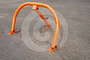 Orange road parking barrier mounted on asphalt