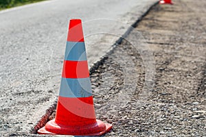 Orange road work cone, indicator on damaged  asphalt road