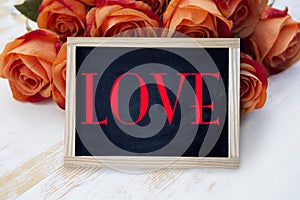 Orange roses and blackboard with the word Love