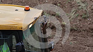 Orange rotating flasher on roof of yellow construction excavator. The concept of attracting attention and security.