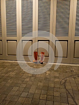 Orange rubber boots in front of a door lonely