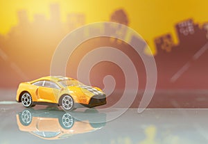 Orange saloon car toy selective focus on blur city background