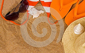 Orange sandals and sunbathing accessories at sand