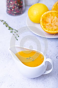 Orange sauce for duck poultry in a white gravy boat.