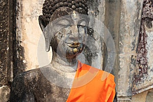 An orange scarf was put on the shoulder of a statue of Buddha (Thailand)