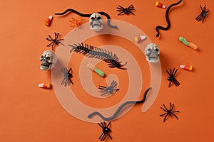 Orange seamless halloweeen background  with white skulls, black snakes, bugs and spiders and halloween candies