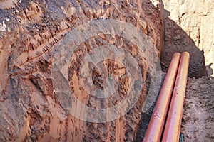 Orange sewer pipes in a trench. Laying communications in the ground during the construction of the building