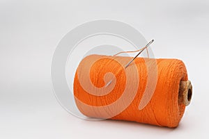 Orange sewing thread with needle on white background