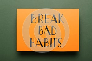 Orange sheet of paper with phrase Break Bad Habits on green background, top view