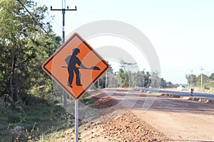 The orange sign shows a symbol with the image of a person holding a shovel on the sign