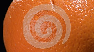 Orange skin fruit gyrating on black background
