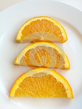 Orange slice isolated on white plate, 3 pieces of fresh sliced orange fruit with skin collection