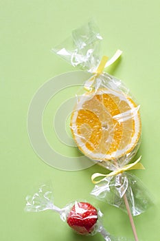 Orange slice on stick and strawberry wrapped in foil, fruit lollipop, candy, healthy substitute for sweets, creative concept