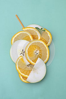 Orange sliced orange and apple fruits, orange juice with cockail straw on blue background. top view