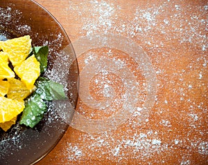 Orange slices with mint leaves on a brown plate and a light brown background