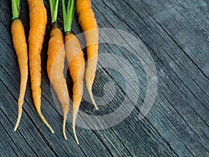 Orange small young carrots on rustic weathered wooden table