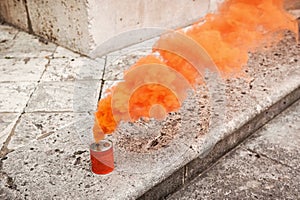 Orange smoke can on stony ground