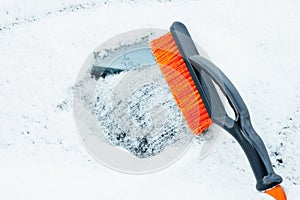 Orange snow brush for car, snowflakes background