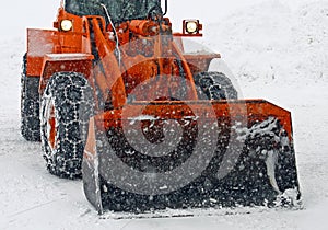 Orange snow plow clears the streets